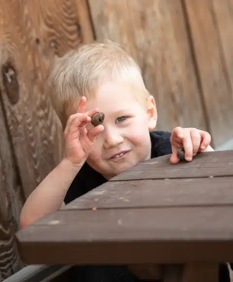 Little Montessori Boy Holding an Acorn To His Eye