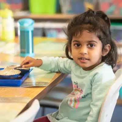 Montessori Girl Sitting at Table Smiling