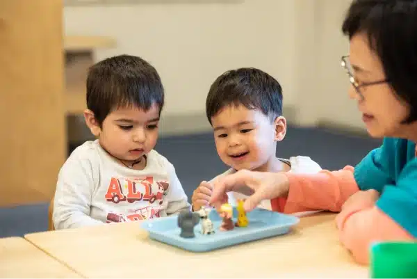 Montessori Toddler Boys Learning at Table With a Teacher